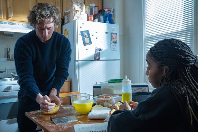 In a scene from Season 2 of FX and Hulu’s The Bear, chef Carmen “Carmy” Berzatto, played by Jeremy Allen White, folds an omelet at the kitchen counter. Chef Sydney Adamu, played by Ayo Edibiri, sits across from him and writes down instructions.